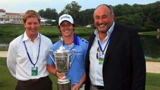 Rory McIlroy of Northern Ireland holds the trophy next to Stuart Cage (L) and Andrew 'Chubby' Chandler after his eight-stroke victory during the 111th U.S. Open