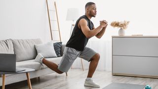 Man performs Bulgarian split squat, using a sofa to elevate his rear foot