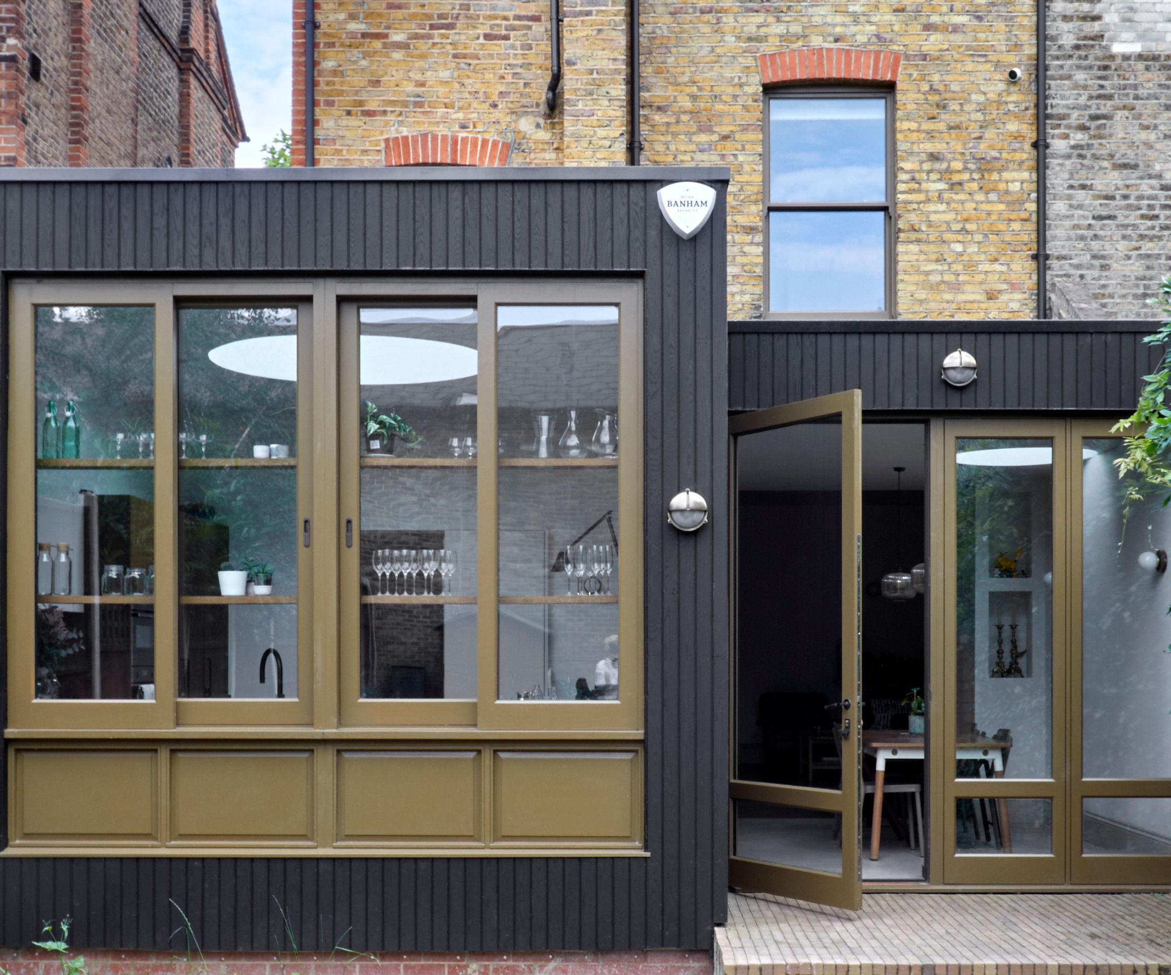 Bold rear extension with dark timber cladding and bronze-coloured aluminium windows and doors, adding contrast to a traditional brick home.