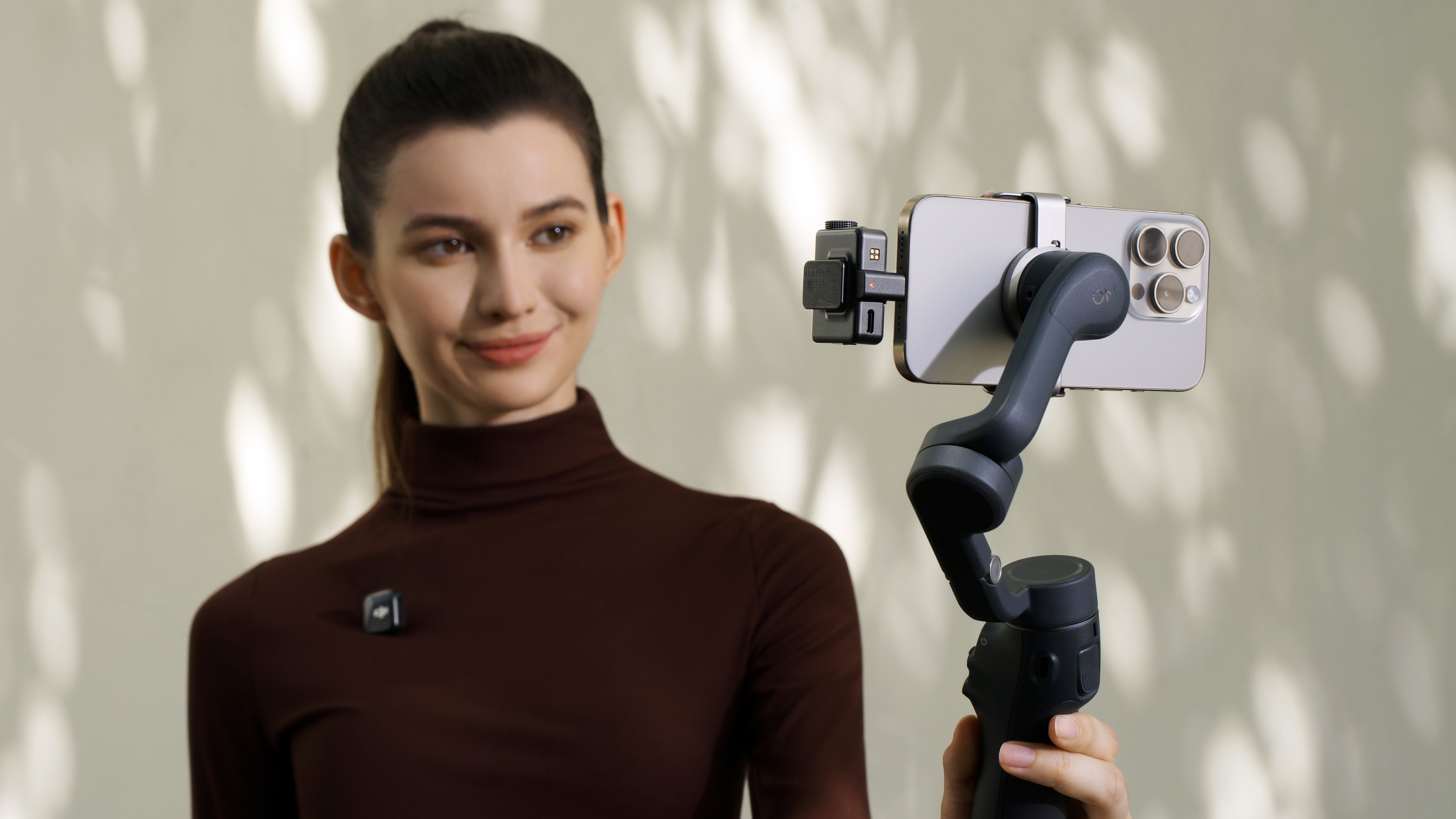 DJI Mic Mini receiver attached to a phone on a gimbal, held by a female content creator