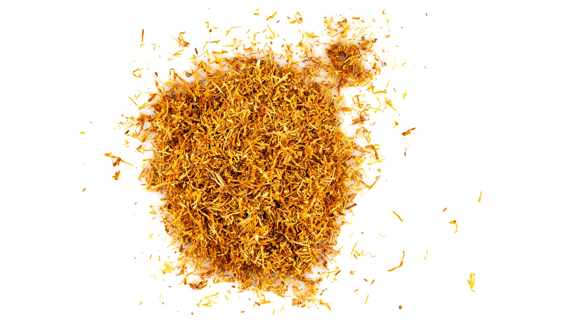 Dried and cut tobacco spread out on a white surface.