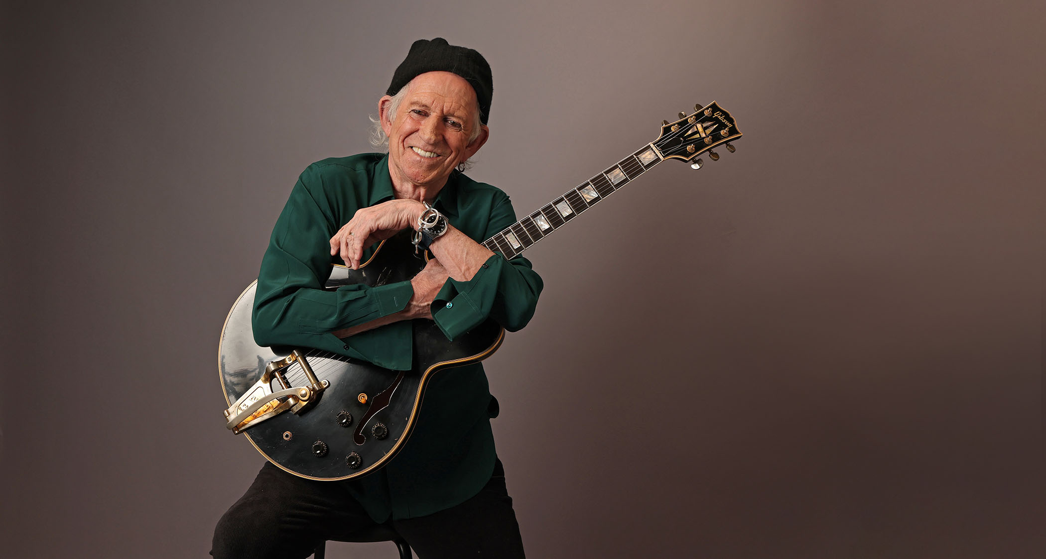 Keith Richards wears a dark green shirt and beanie and cradles his black 1960 Gibson ES-355.