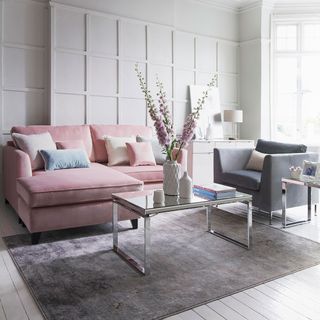 living room with white wall and wooden floor and pink and grey sofa with cushions