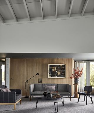 A living room with wood paneling and grey carpet