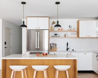 Kitchen lighting ideas with black pendants in a white and light oak apartment kitchen