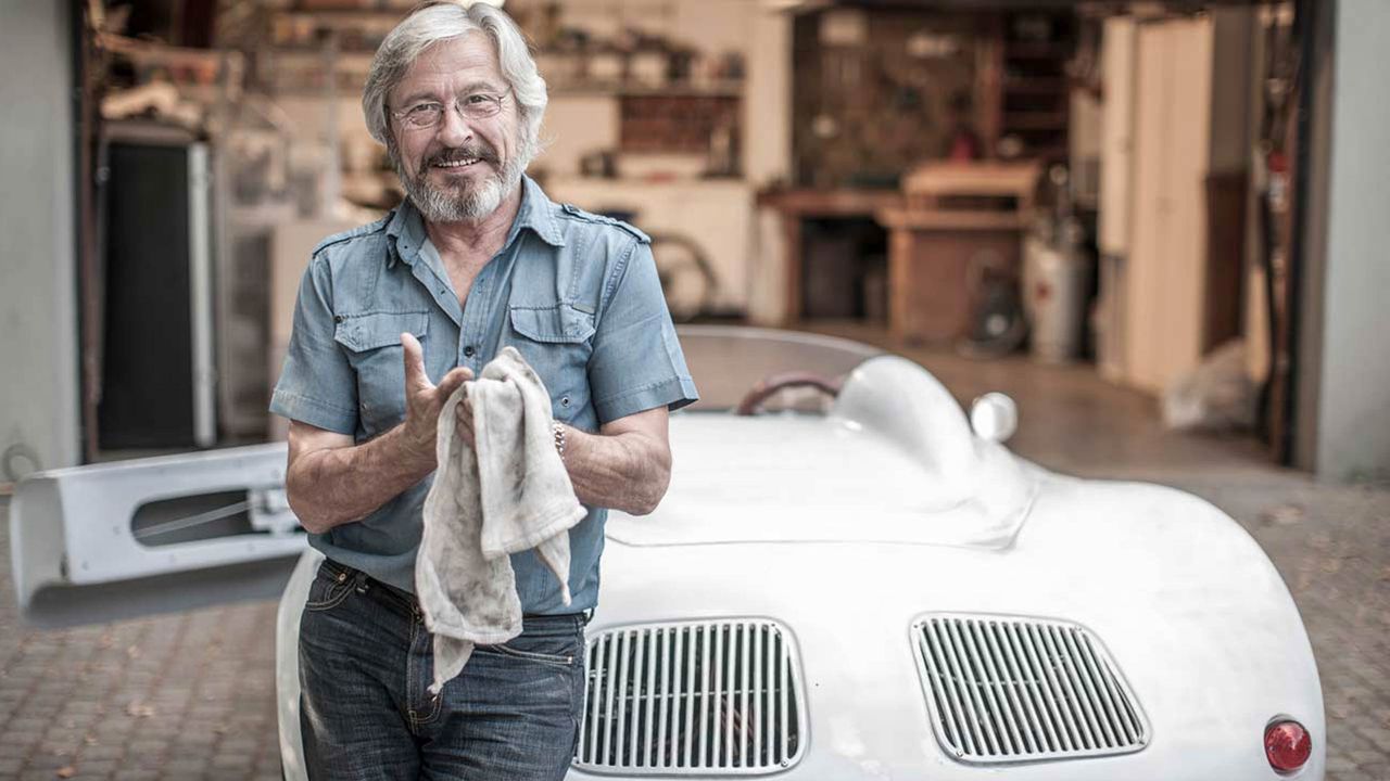 A wealthy man works on his sportscar.