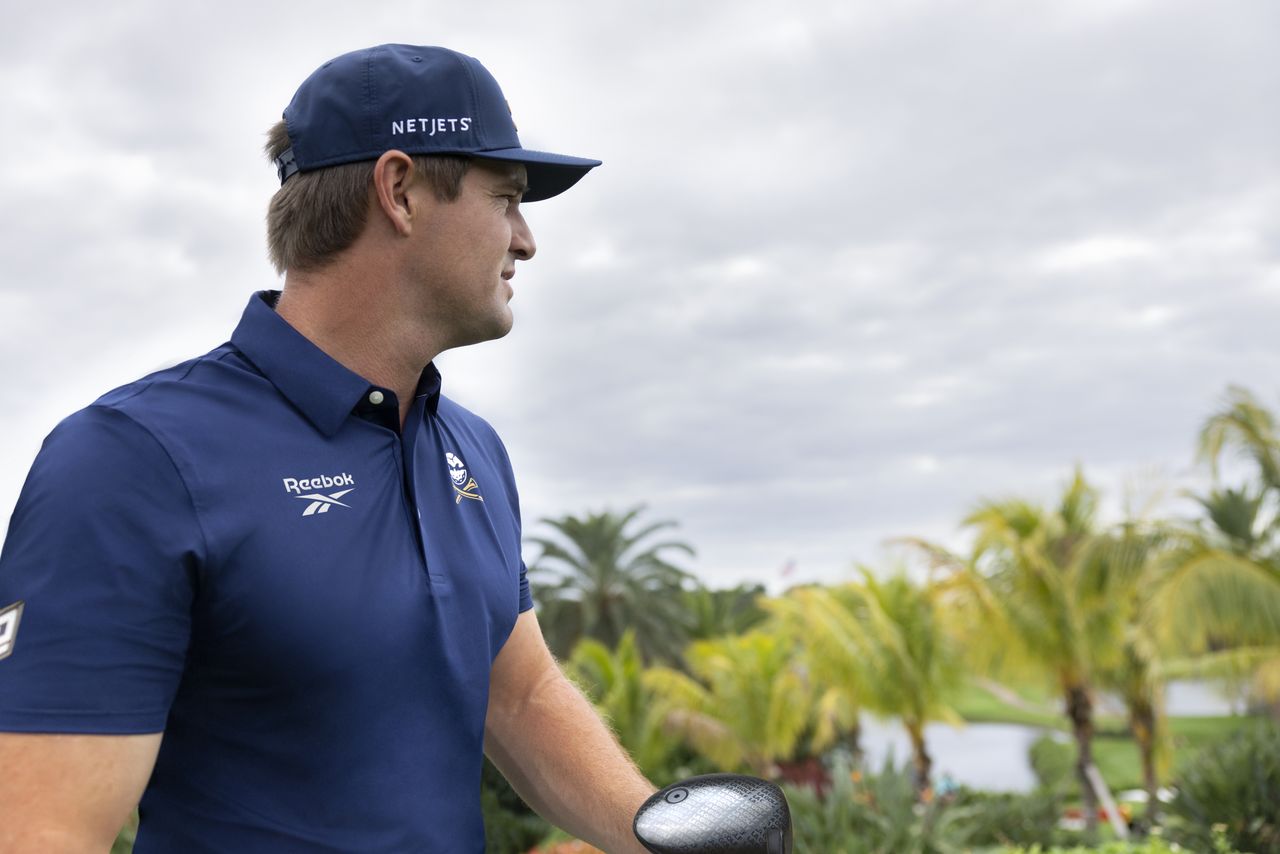 Bryson DeChambeau poses in Reebok gear and an LA Golf driver