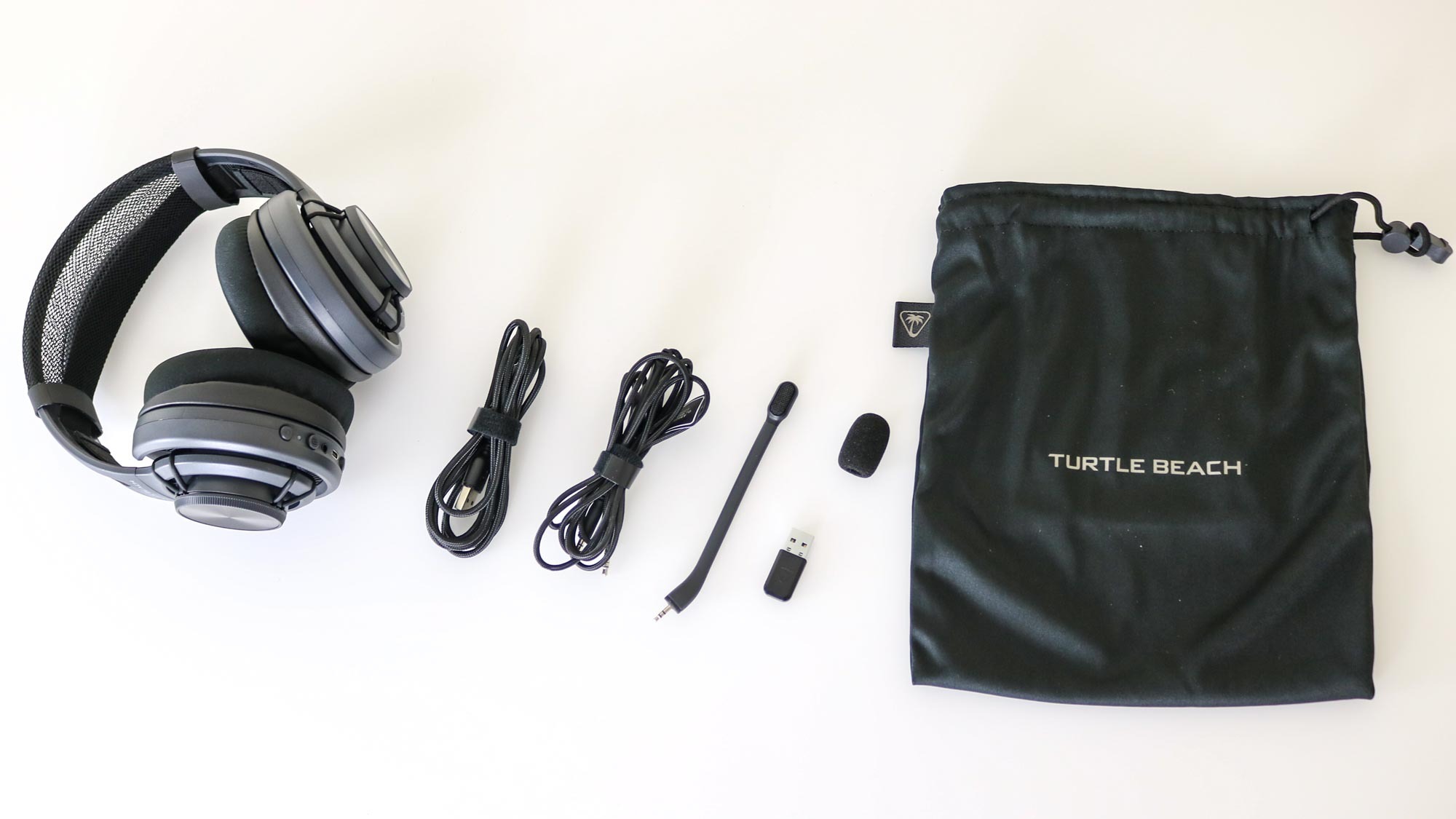 The Turtle Beach Atlas Air on a desk along with all of the included accessories and its carrying pouch