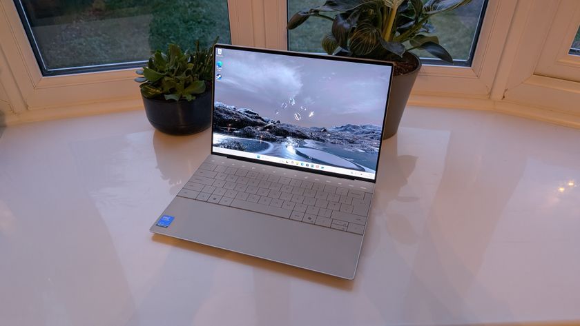 The Dell XPS 13 pictured on a white surface in front of a window with two potted plants.