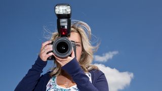 Woman holding Canon EOS 7D DSLR with flashgun