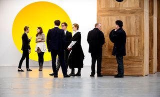 Visitors stand before a giant yellow disc