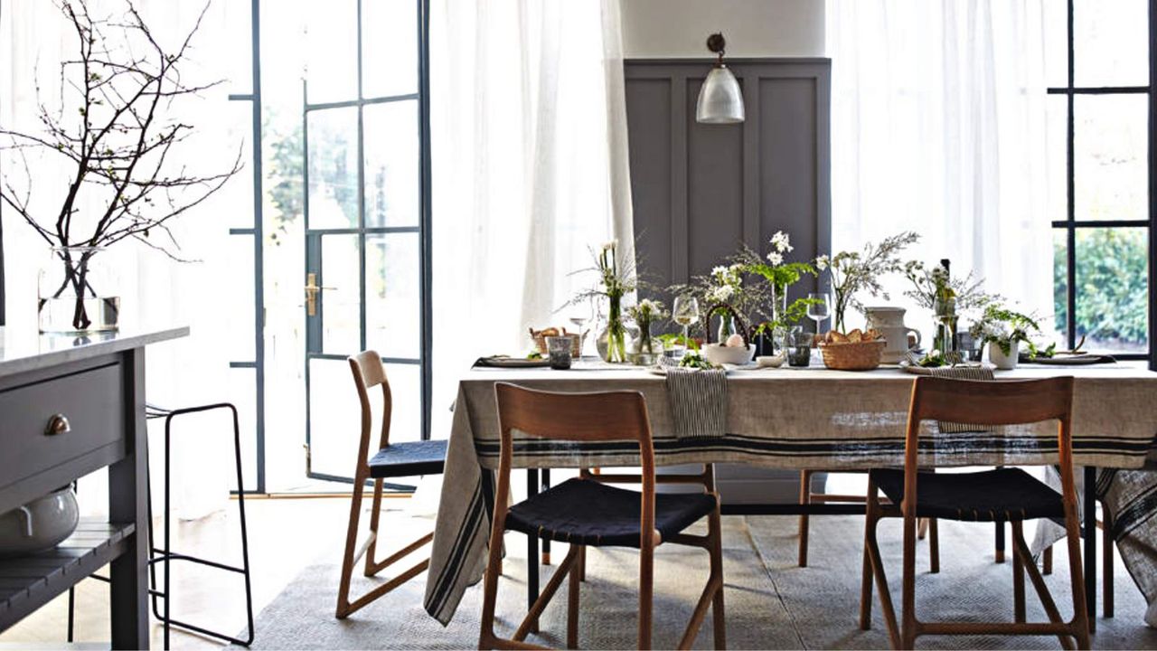  Grey and white dining room with retro chairs and table with tablecloth laid with spring flower displays