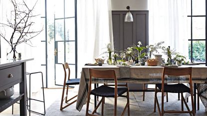  Grey and white dining room with retro chairs and table with tablecloth laid with spring flower displays