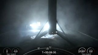 a spacex rocket rests on the deck of a drone ship at night.