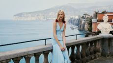 A woman in a blue dress poses on the balcony at Grand Hotel Excelsior Vittoria