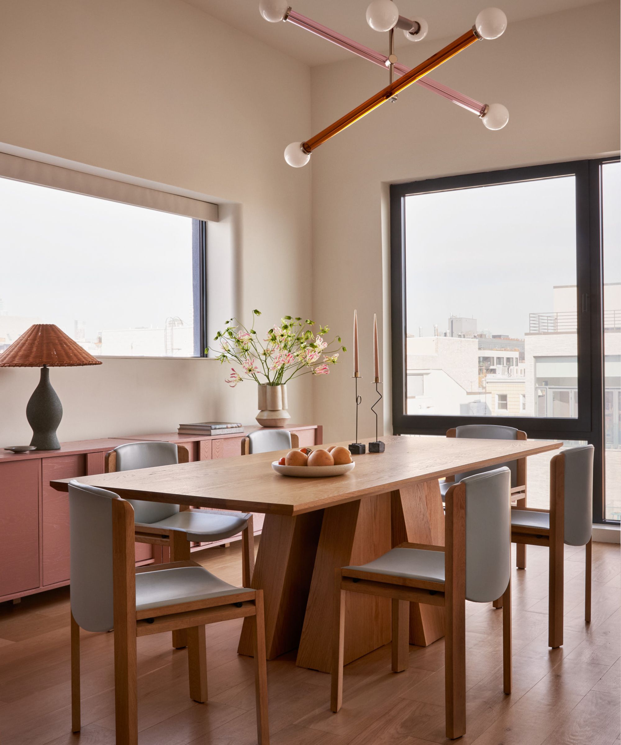 Dining room with wood table, midcentury chairs, abstract light, wood console with rattan lamp and vase