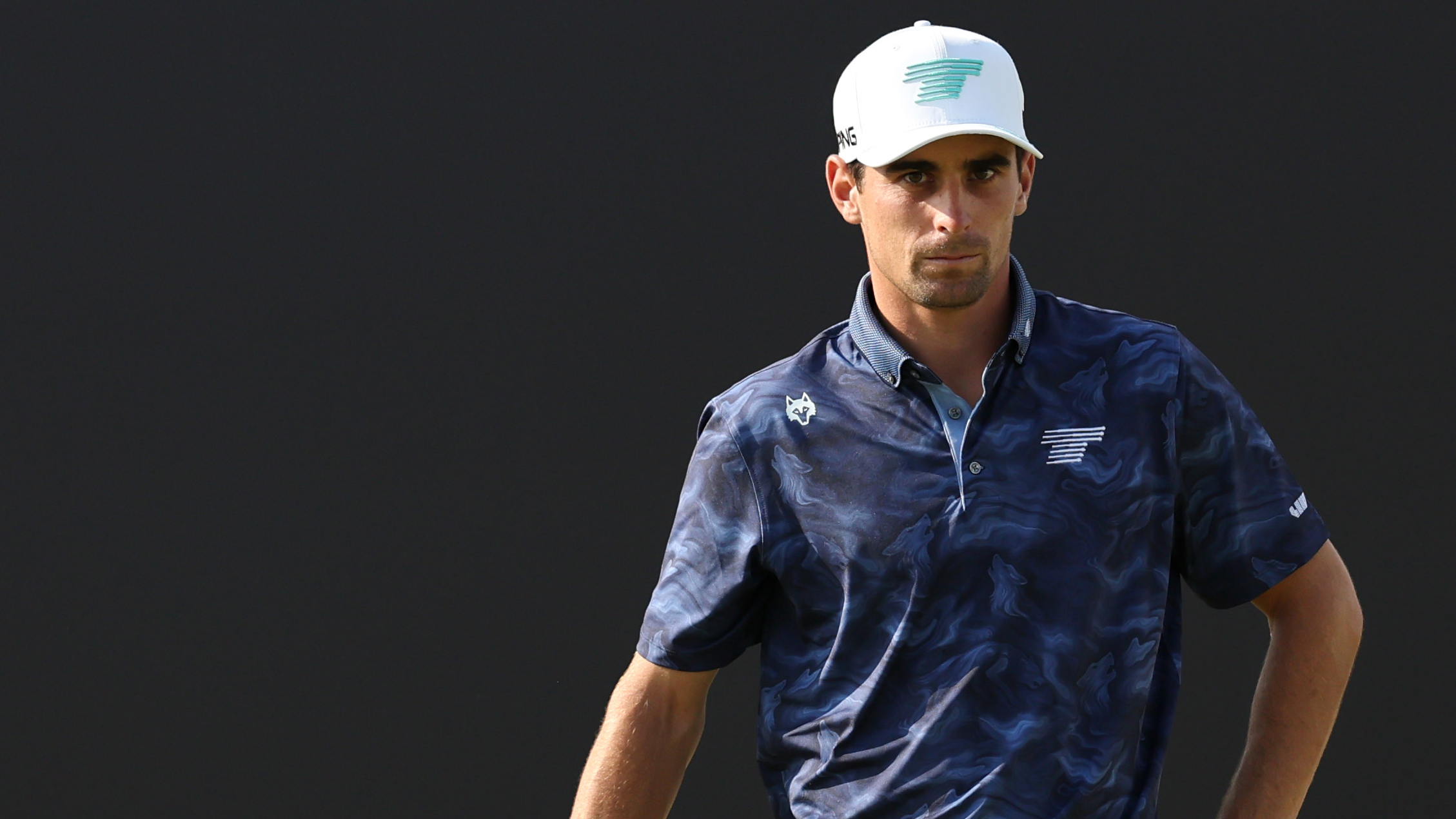 Joaquin Niemann wearing a blue camo polo shirt and white cap