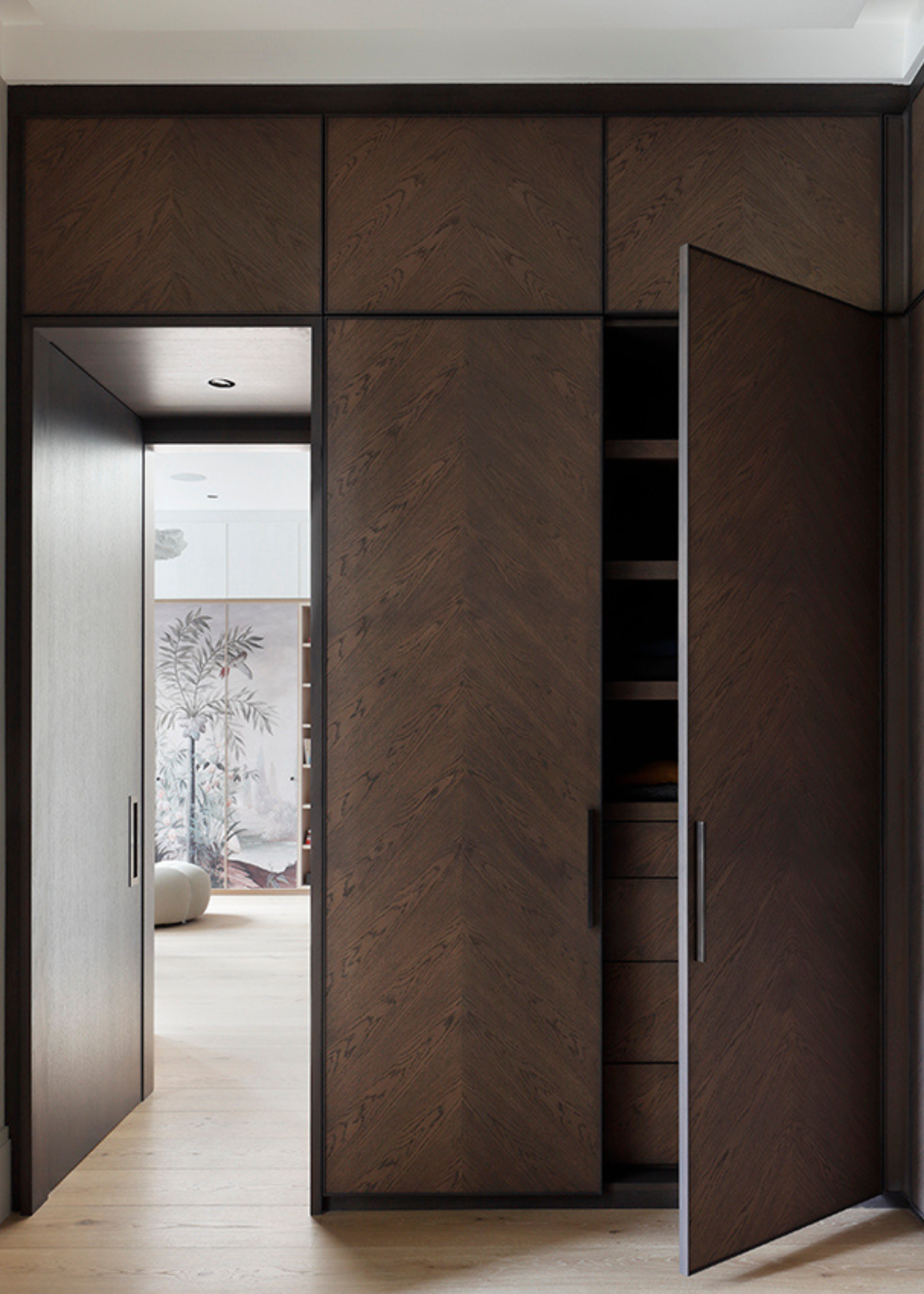 A bedroom with a dark wood closet with a door left ajar