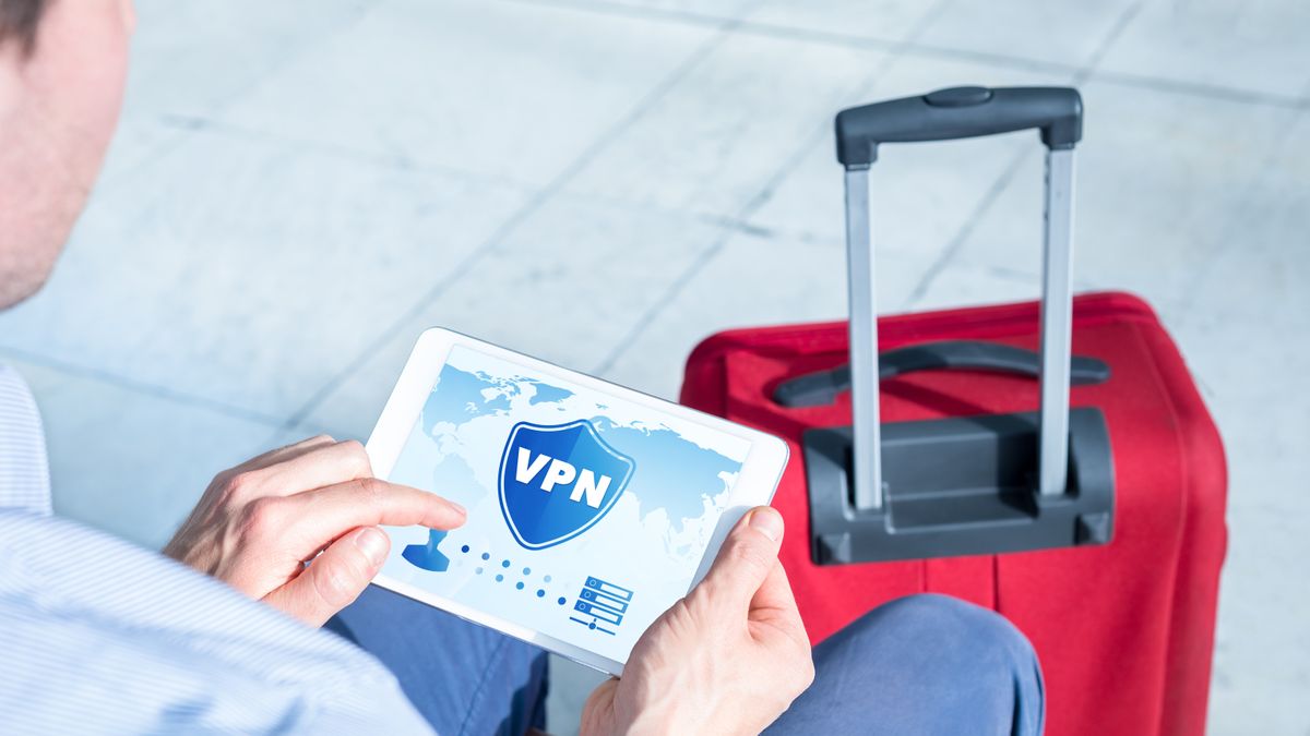 A man using a VPN in an airport next to red luggage