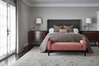 Grey bedroom with brown wood drawers and an upholstered bed in charcoal