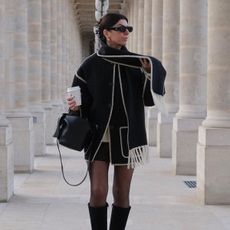 Woman wears toteme coat and black boots