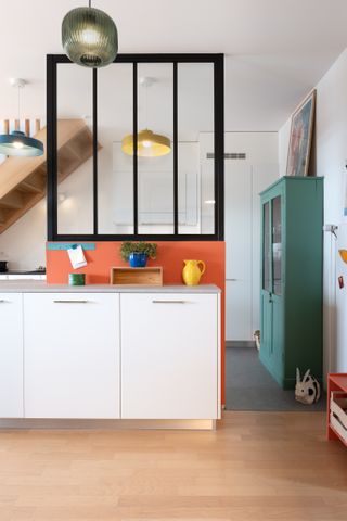 A window small square window placed between a kitchen and living room space