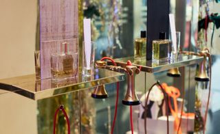 Perfume bottles on display on gold shelves in front of mirrors