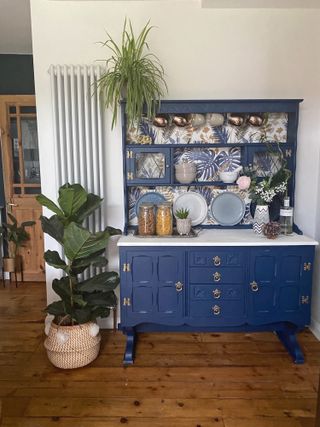Kitchen dresser painted blue with floral wallpaper backing