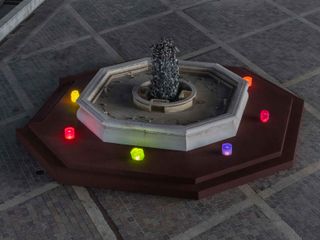 coloured lights set around central fountain in square in Bergamo, part of installation by Objects of Common Interest