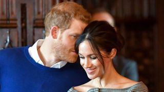 Britain's Prince Harry whispers to his fiancée US actress Meghan Markle as they watch a performance by a Welsh choir during a visit at Cardiff Castle in Cardiff, south Wales on January 18, 2018, for a day showcasing the rich culture and heritage of Wales. / AFP PHOTO / POOL / Ben Birchall (Photo credit should read BEN BIRCHALL/AFP via Getty Images)