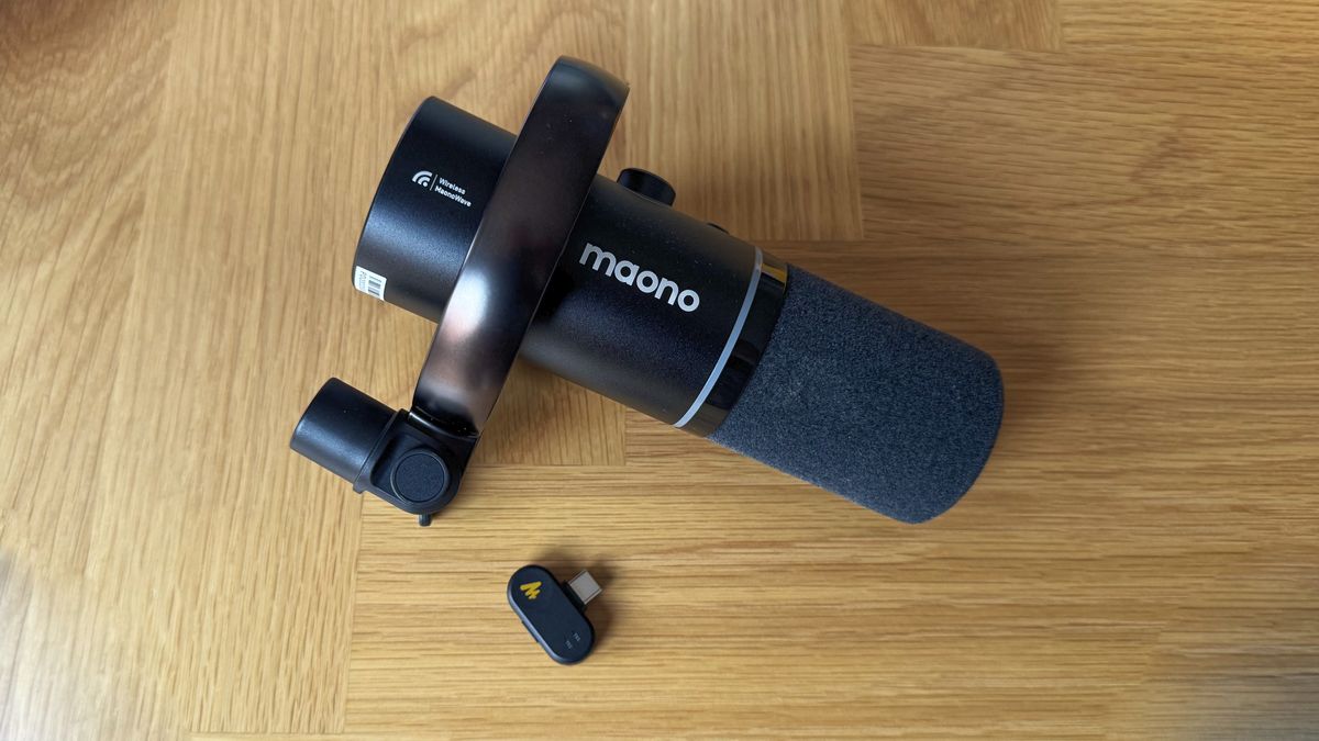 A Maono PD200W microphone lying on a desk next to its wireless receiver