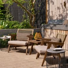 A garden with a set of wooden lounge chairs with woven backrests and a matching side table