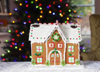 Decorated gingerbread house in front of a Christmas tree