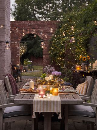 outdoor summer dinning setting with festoons and candles in a courtyard