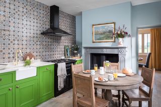 Green and blue kitchen with tiled splashback and fireplace