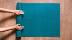 Woman's hands rolling up Pilates mat at home after doing Pilates every day