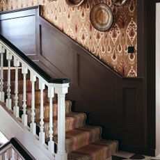 Staircase with striped runner, Indian inspired wallpaper and woven basket wall decoration