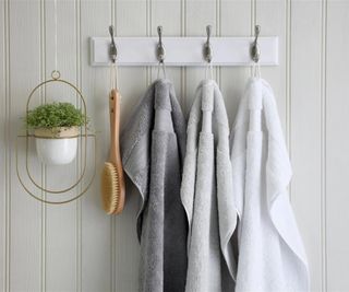Three Egyptian cotton towels hanging from hooks in a bathroom.