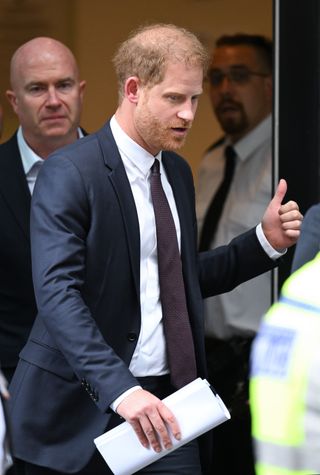 Prince Harry gives a thumbs up as he exits a courtroom