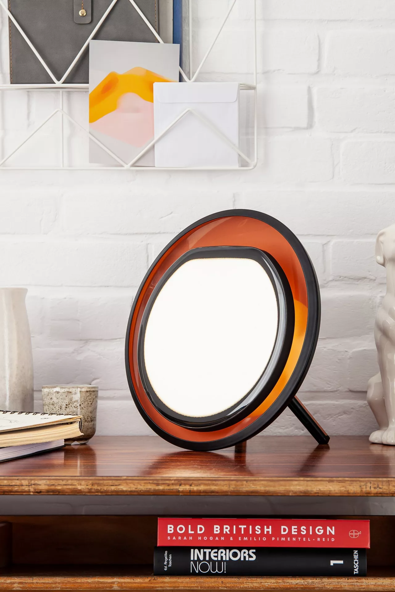 A halo lamp on a wood side table with coffee table books