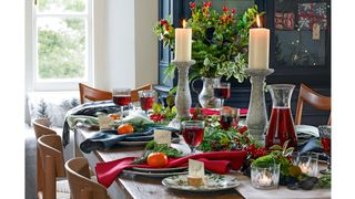 Dining table with Christmas centerpiece idea with natural foliage and large pillar candle sticks