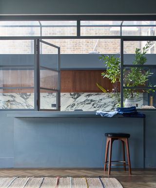 blue/gray kitchen with modern design, marble backsplash and parquet flooring, rug, stool, open plan feel,