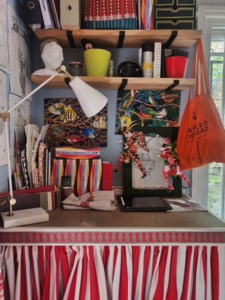 desk in colorful room with embroidered artwork and striped curtains under desk