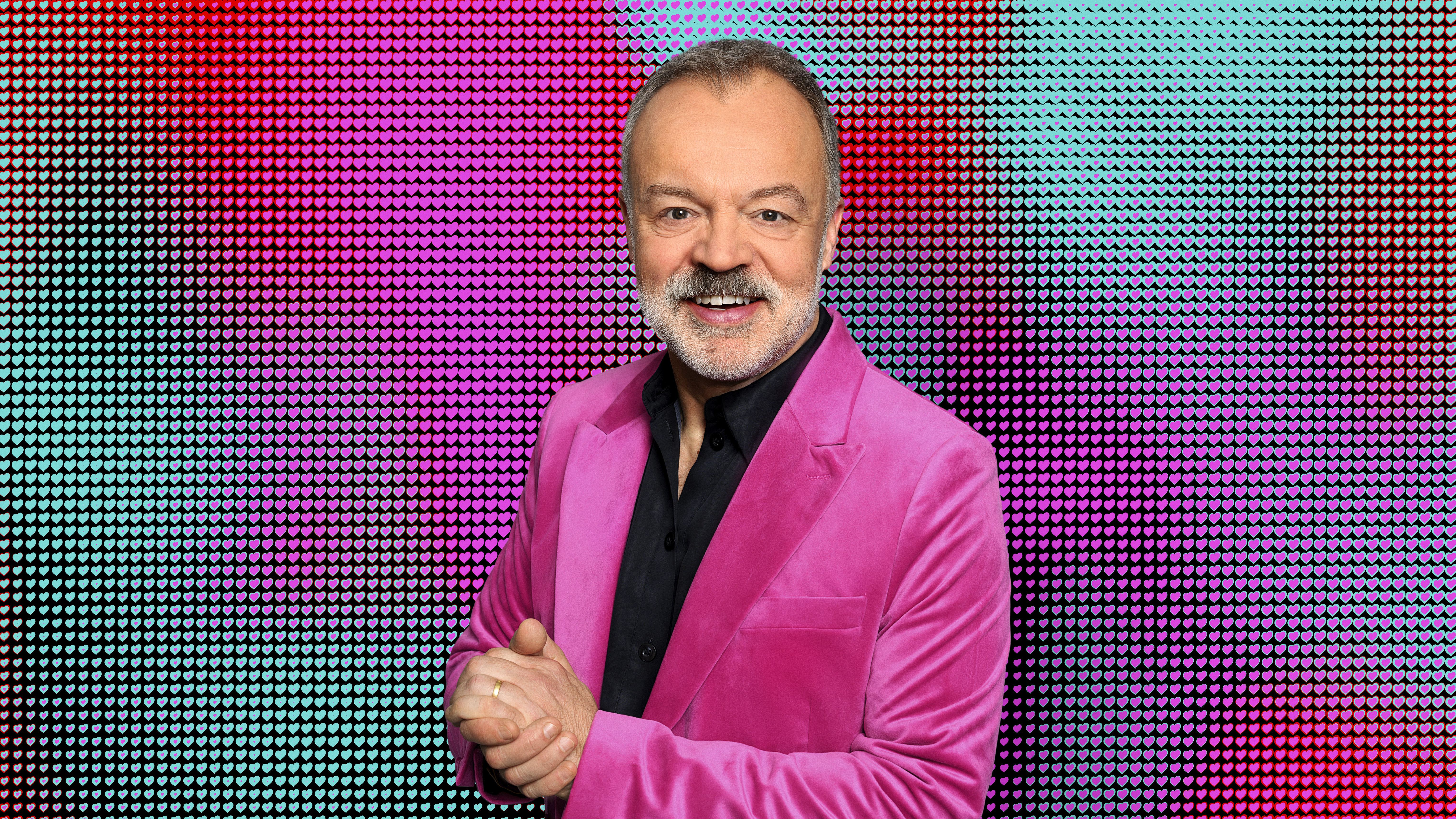 Graham Norton in a pink jacket and smiling to the camera for Eurovision 2025