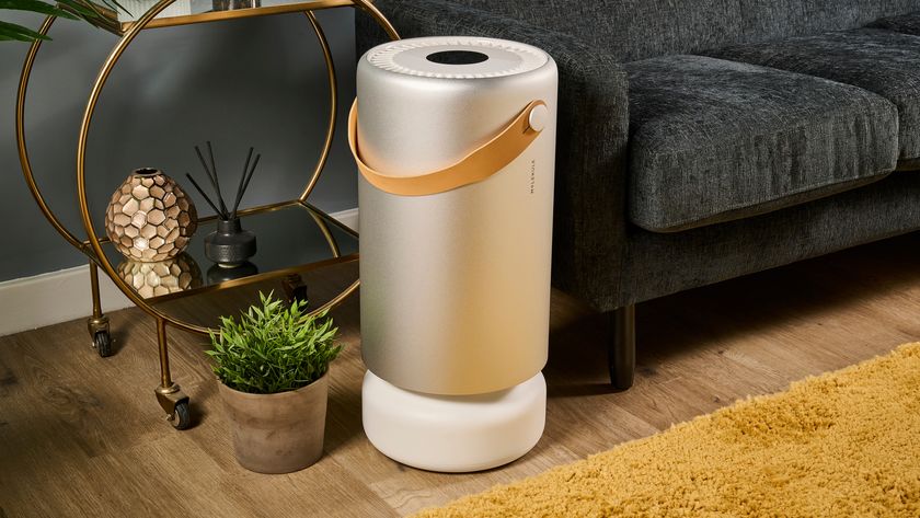 Image shows the Molekule Air Pro air purifier sitting on a mustard colored rug in a living room.