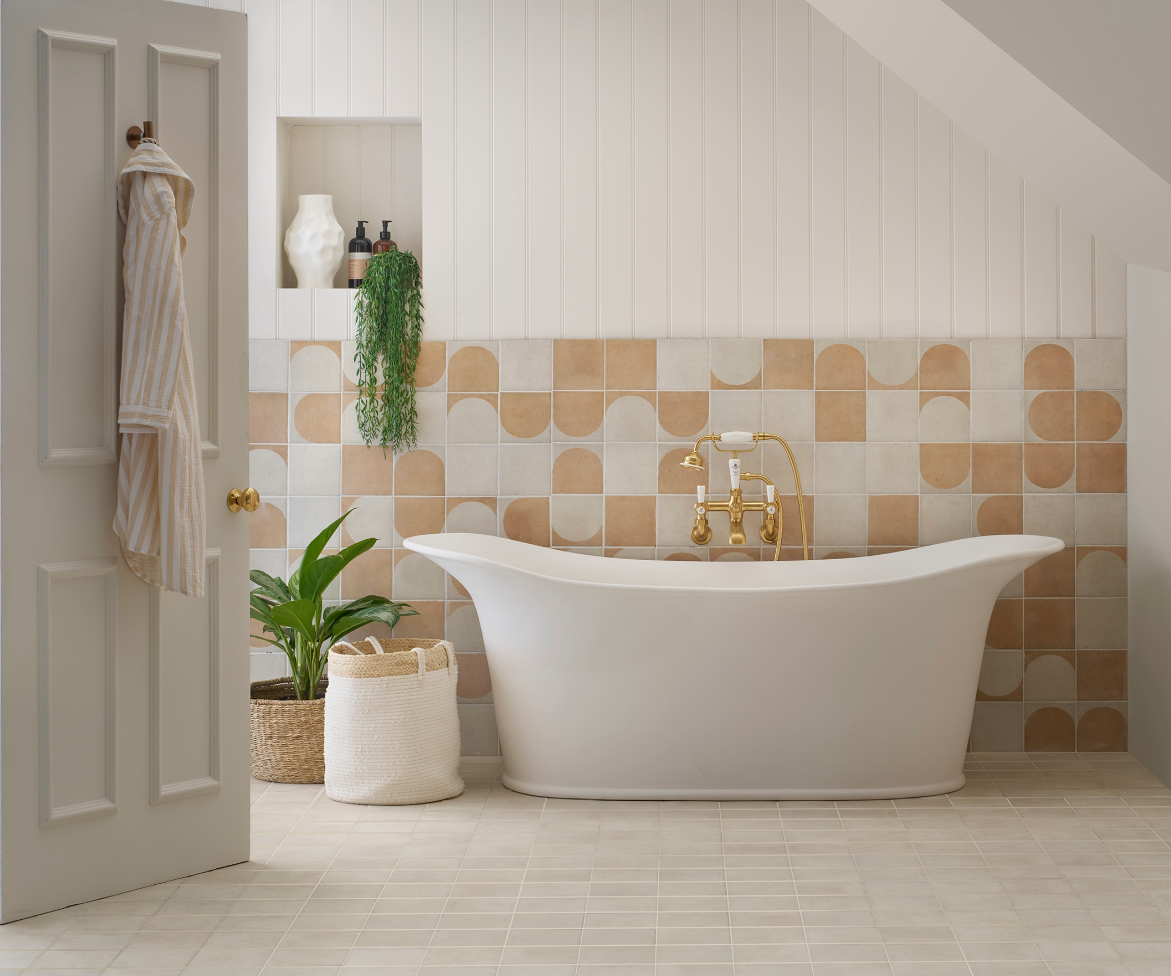 Neutral bathroom with freestanding bath and a patterned tiled feature wall behind it