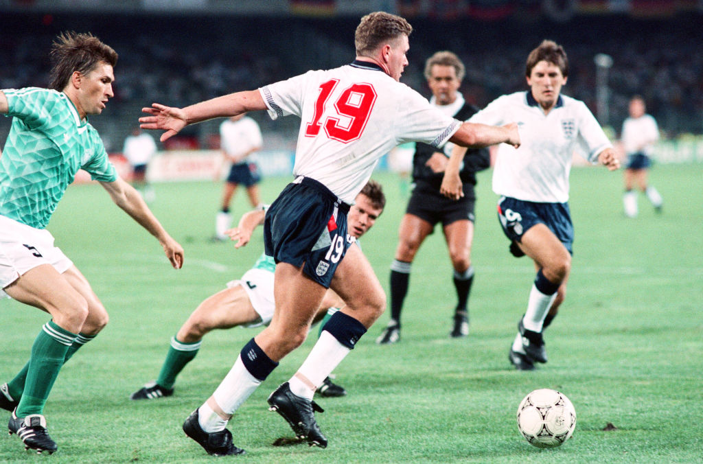 1990 World Cup Semi Final match the Stadio delle Alpi in Turin, Italy. West Germany 1 v England 1 (west Germany won on penalties). England's Paul Gascoigne steps away from Klaus Augenthaler (left) and Lothar Mattheus during the match watched by Peter Beardsley, 4th July 1990.