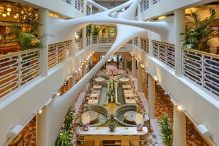 A futuristically design restaurant features a stretched sculptural ceiling in white plaster and 1970s-inspired furniture.