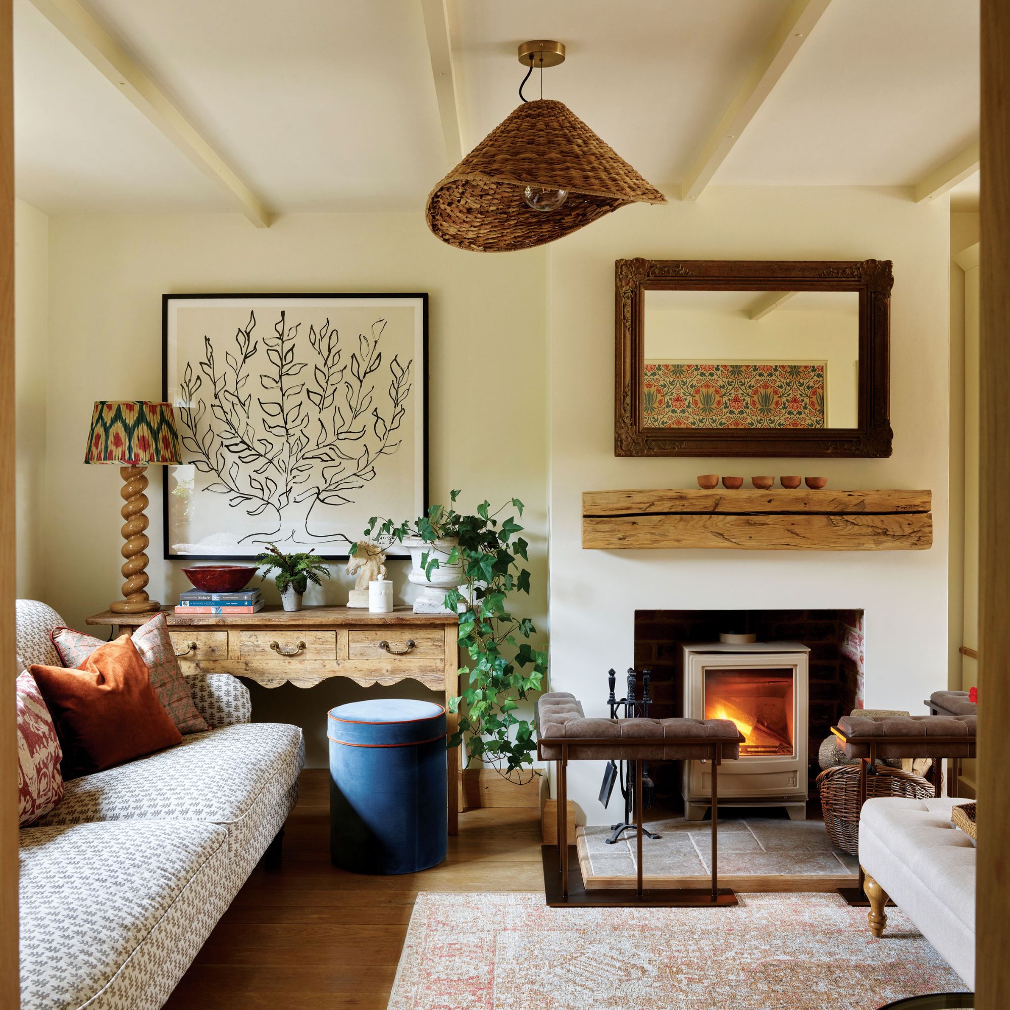 Cream living room with wooden accents and floor, rattan light and fireplace with light coloured rug and ottoman