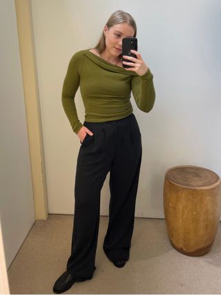 Woman wears green top and black tailored trousers